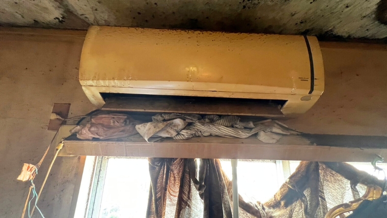 自社スタッフが撮影した賃貸物件のエアコン。本体・天井・壁面全体に黒カビと汚損が広がった実際の現場写真