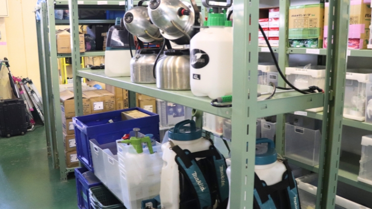 ブルークリーン株式会社の資材倉庫に整備された噴霧器・makita製背負い式散布機・薬剤類が棚に整然と保管されている様子