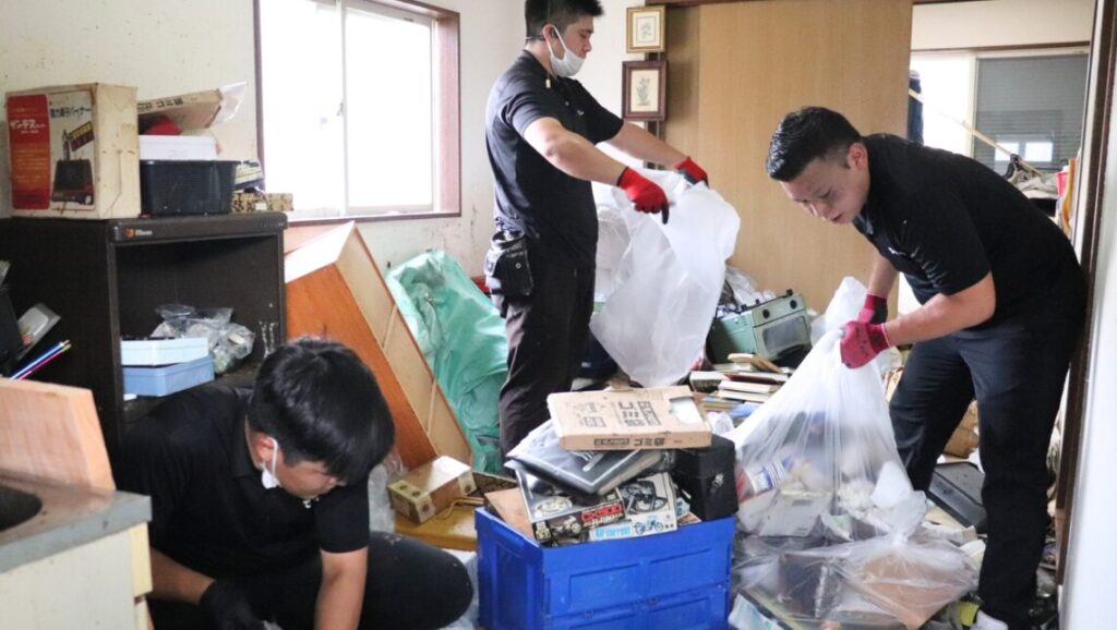 荷物やゴミが散乱した室内で、袋詰め作業を行う自社スタッフ3名の実際の作業の様子