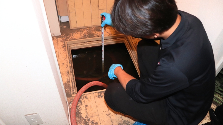 ベタ基礎の床下浸水において、ブルークリーンのスタッフが専用機器で水分量や浸水状況を計測している様子