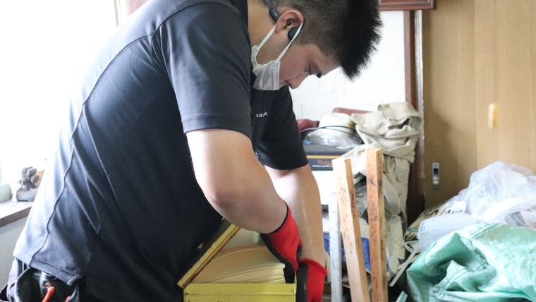 マスク・ゴーグル・赤いゴム手袋を着用したブルークリーンスタッフが、荷物の中に紛れた貴重品を実際に確認・仕分けしている様子