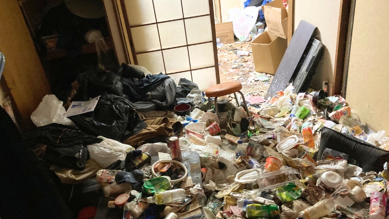 自社スタッフが撮影したゴミ屋敷の実際の現場。食品容器・缶・ゴミ袋が和室から廊下まで床一面に堆積した重度の汚染状態