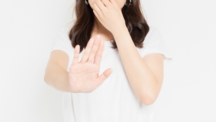 鼻を手で覆い片手を前に突き出して匂いを拒絶するジェスチャーをしている女性と思われる人物のイメージ。強烈な匂いに困惑する状況を想起させる