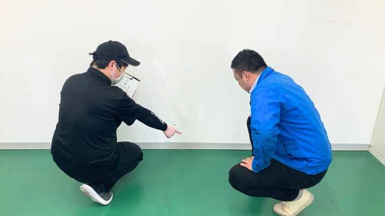 ブルークリーンスタッフ2名が現場の壁面・床面の状態を確認しながら打ち合わせをしている様子。孤独死現場の特殊清掃における現地調査・見積もり工程のイメージ