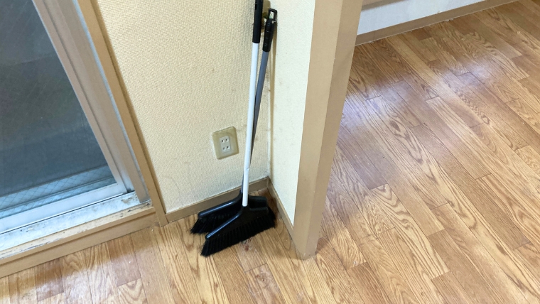 居室内のベランダ近くに箒が立てかけられている様子